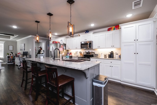 kitchen with visible vents, stainless steel appliances, a center island with sink, dark wood-type flooring, and a kitchen breakfast bar