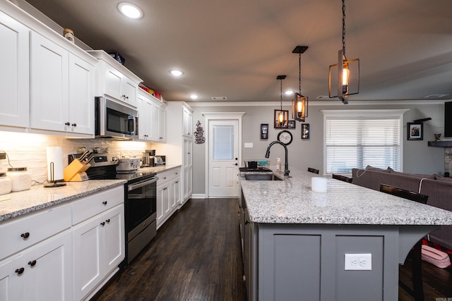 kitchen with light stone counters, a sink, tasteful backsplash, stainless steel appliances, and a kitchen island with sink