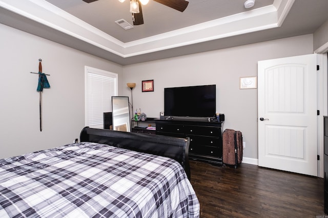 bedroom with dark wood-style flooring, a tray ceiling, ceiling fan, and visible vents