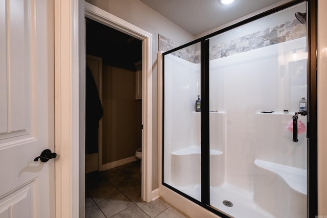 bathroom featuring toilet, tile patterned floors, and a shower stall