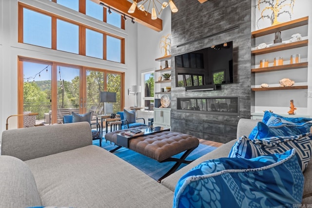 living area featuring a high ceiling, a tiled fireplace, wood finished floors, and built in features