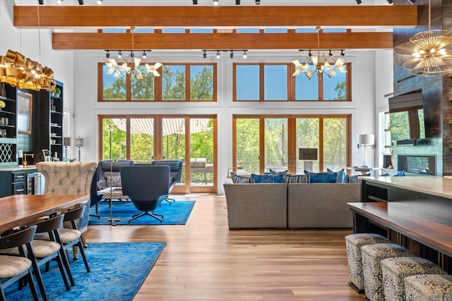 living area featuring wood finished floors, a towering ceiling, and a chandelier