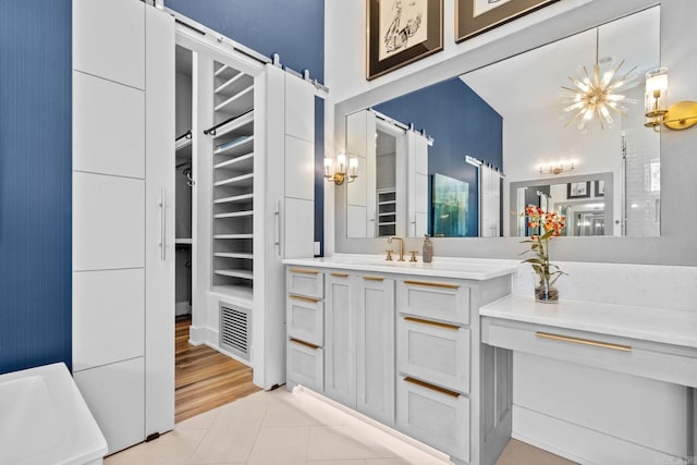 bathroom featuring a spacious closet, an inviting chandelier, tile patterned floors, and vanity