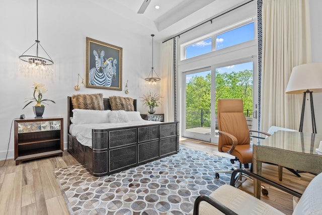 bedroom with a chandelier, baseboards, a towering ceiling, access to outside, and wood finished floors