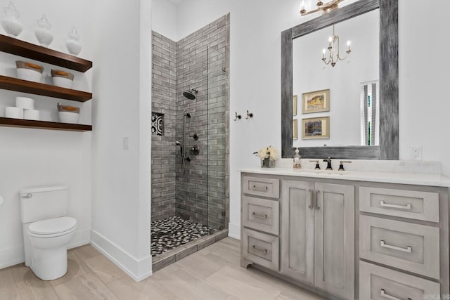 full bathroom featuring baseboards, toilet, vanity, a stall shower, and a notable chandelier
