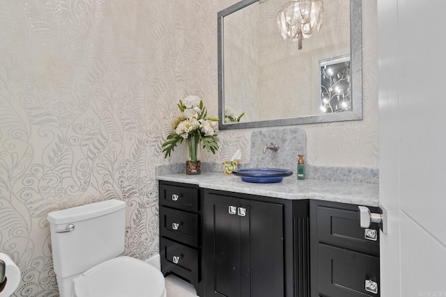 half bath with wallpapered walls, vanity, and toilet