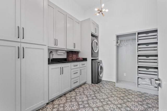 clothes washing area with a sink, cabinet space, stacked washer / dryer, and a chandelier
