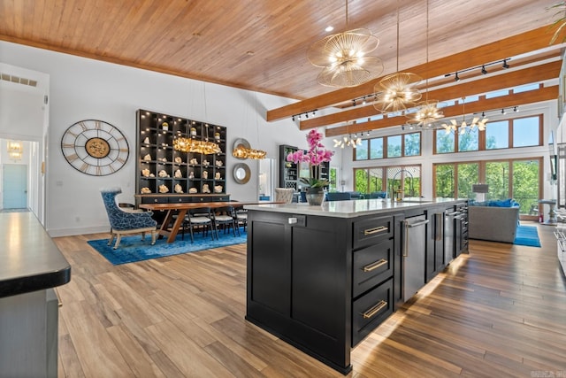kitchen with open floor plan, dark cabinetry, a chandelier, a sink, and light wood-style flooring