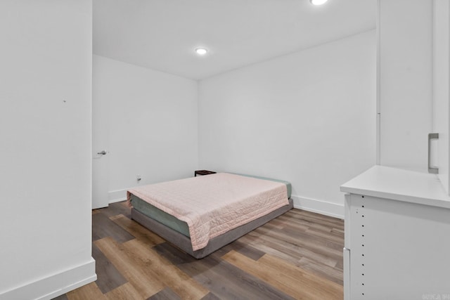 bedroom featuring baseboards, wood finished floors, and recessed lighting