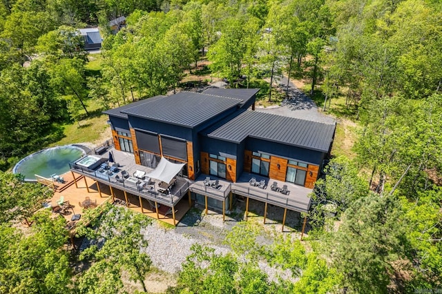 back of house with metal roof, a standing seam roof, and a deck