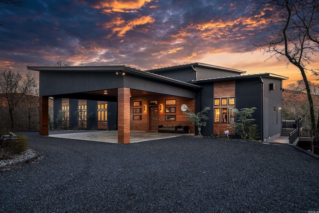 rear view of house with driveway, a carport, and a patio