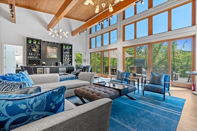 living room featuring wooden ceiling, beam ceiling, a chandelier, a towering ceiling, and hardwood / wood-style floors