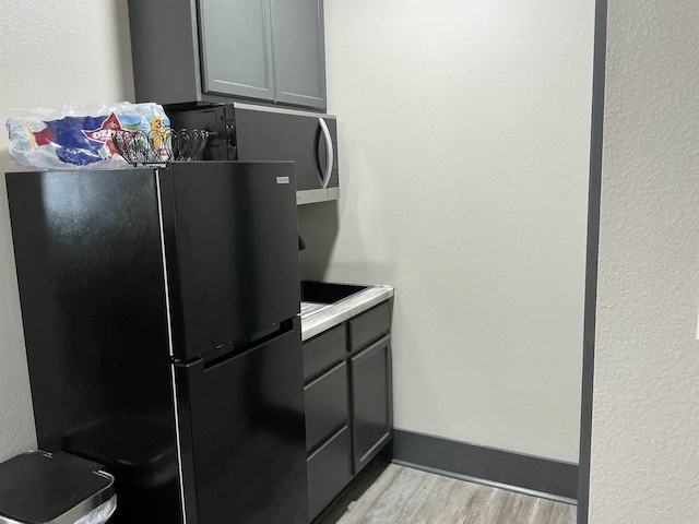 206 W High St, Sheridan, AR 72150 - kitchen with freestanding refrigerator, light wood finished floors, gray cabinets, light countertops, and a textured wall