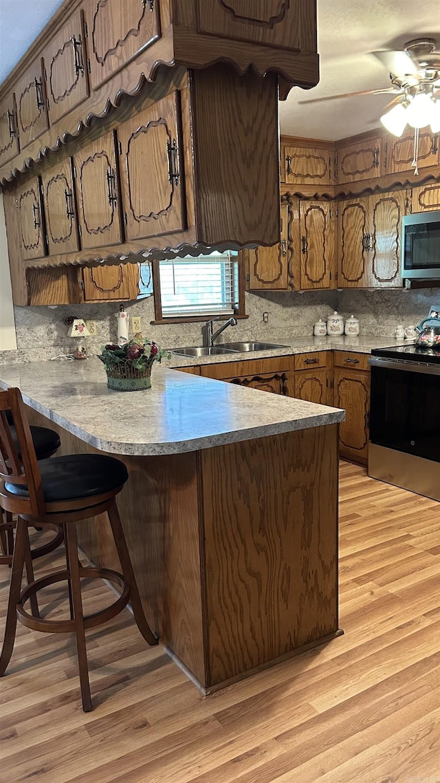 164 Polk Road 714, Mena, AR 71953 - kitchen featuring light wood-style flooring, a peninsula, stainless steel appliances, tasteful backsplash, and a sink
