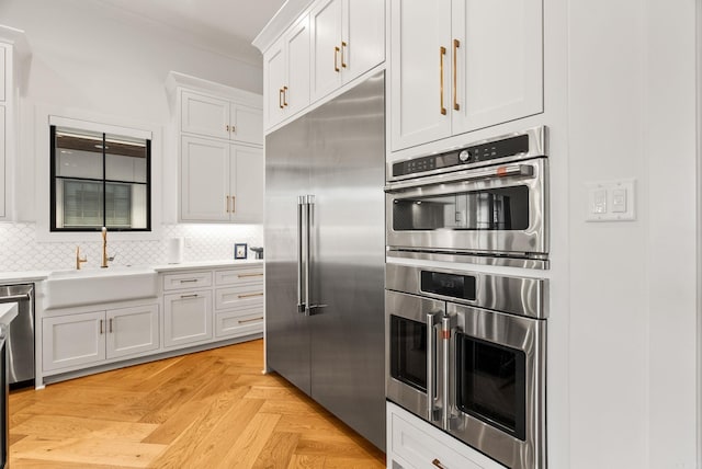 5204 Stonewall Rd, Little Rock, AR 72207 - kitchen featuring tasteful backsplash, crown molding, a sink, white cabinets, and appliances with stainless steel finishes