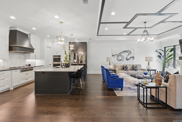 125 Hallen Ln, Little Rock, AR 72223 - kitchen with stainless steel gas stovetop, open floor plan, dark wood-style floors, wall chimney range hood, and a notable chandelier