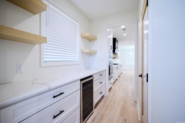 9 Marchwood Cv, Little Rock, AR 72210 - kitchen with wine cooler, open shelves, light wood-style flooring, white cabinets, and oven