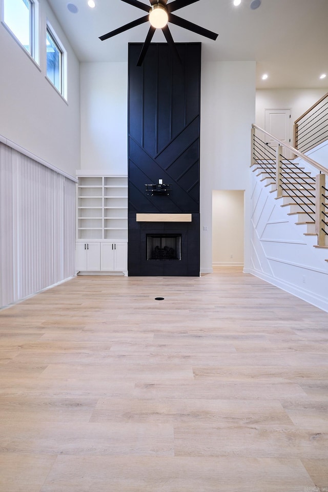9 Marchwood Cv, Little Rock, AR 72210 - unfurnished living room with stairway, a fireplace, light wood-type flooring, ceiling fan, and a towering ceiling