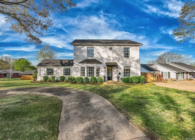 view of front of home with a front yard, concrete driveway, stucco siding, and fence