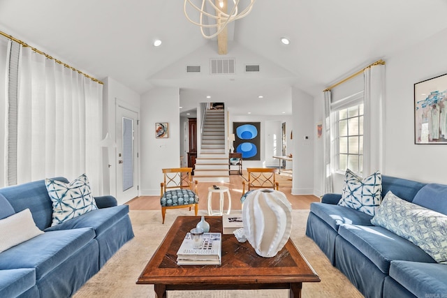 living room featuring light wood finished floors, stairway, vaulted ceiling, and visible vents