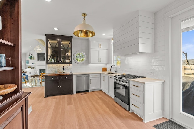 kitchen featuring light wood finished floors, a sink, white cabinetry, and appliances with stainless steel finishes