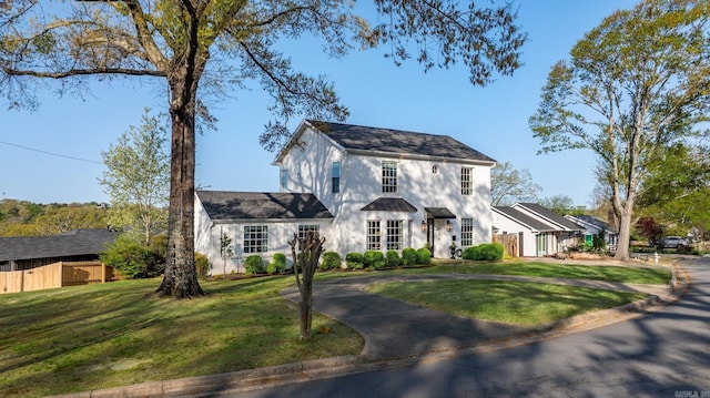 view of front of house with fence, concrete driveway, and a front yard