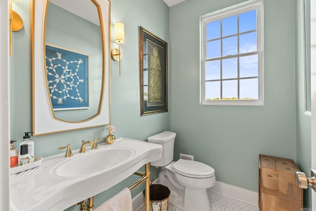 bathroom featuring baseboards, toilet, tile patterned flooring, and a sink