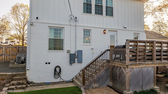 back of property featuring stairway, central air condition unit, a wooden deck, fence, and brick siding