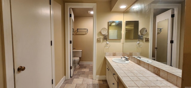 bathroom with toilet, vanity, and baseboards