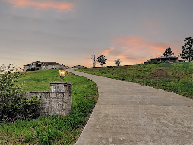 surrounding community featuring driveway, a lawn, and a rural view