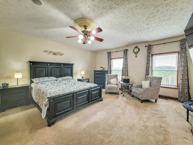 bedroom featuring ceiling fan, light colored carpet, and a textured ceiling