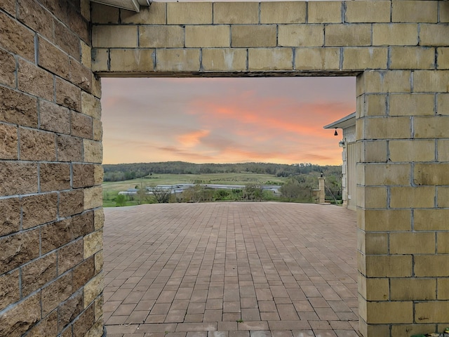 patio terrace at dusk featuring a rural view