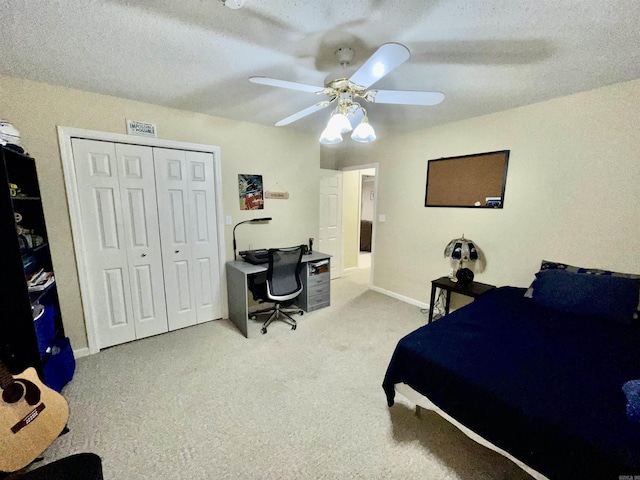 bedroom with a closet, carpet floors, a textured ceiling, baseboards, and ceiling fan