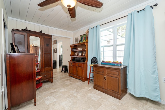 office with ornamental molding, wooden ceiling, wood walls, and ceiling fan