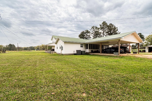 exterior space featuring a lawn, metal roof, a carport, and central AC