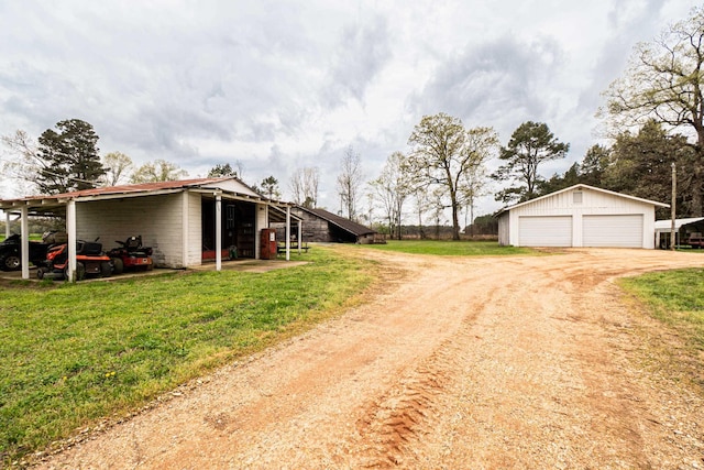 exterior space featuring a detached garage, an outbuilding, driveway, and a front lawn