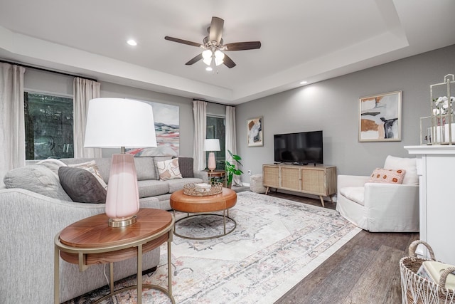 living area featuring wood finished floors, recessed lighting, a ceiling fan, and a raised ceiling