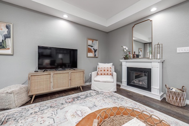living room featuring baseboards, recessed lighting, wood finished floors, and a glass covered fireplace