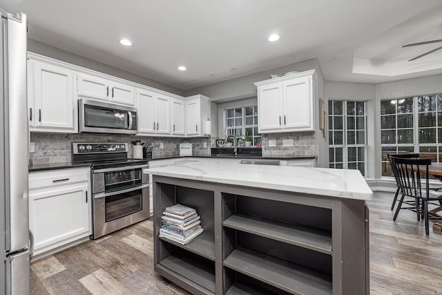 kitchen featuring white cabinetry, light wood-style flooring, appliances with stainless steel finishes, and open shelves