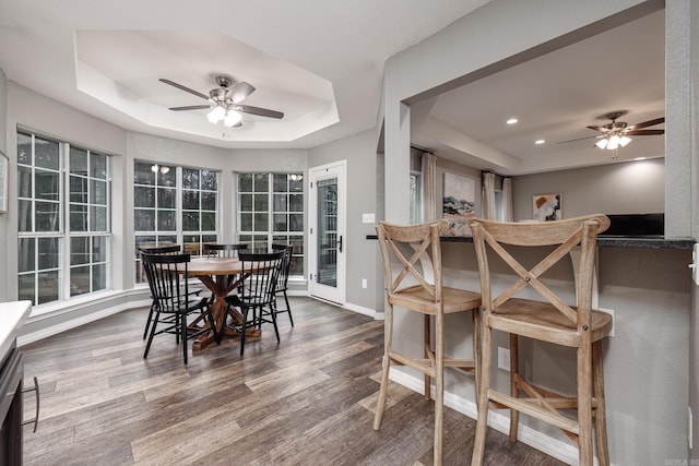 dining room featuring baseboards, a tray ceiling, wood finished floors, and a ceiling fan
