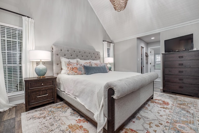 bedroom with connected bathroom, lofted ceiling, crown molding, and wood finished floors