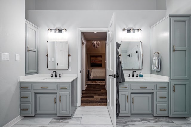 ensuite bathroom with marble finish floor, a sink, and two vanities