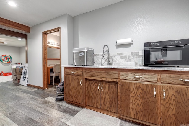 kitchen featuring light countertops, light wood finished floors, oven, a sink, and brown cabinetry