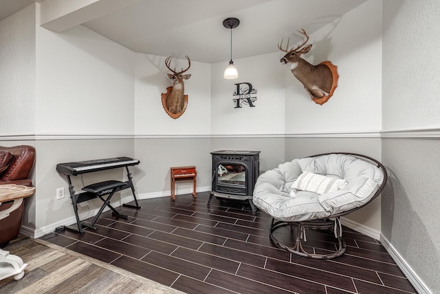 living area featuring wood tiled floor, baseboards, and a wood stove