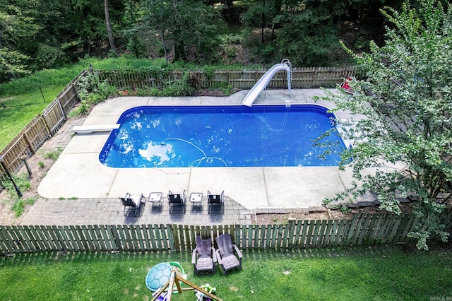 view of pool with a water slide, a fenced in pool, a fenced backyard, a diving board, and a patio area