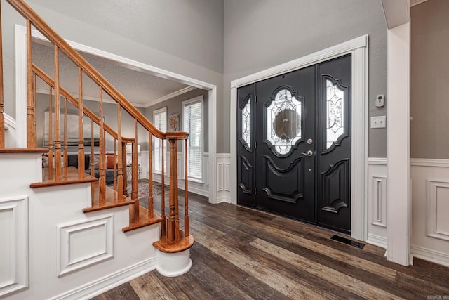 entrance foyer with a wainscoted wall, dark wood-style floors, stairs, and crown molding