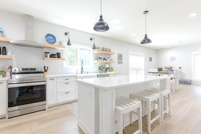 kitchen featuring light countertops, exhaust hood, appliances with stainless steel finishes, and open shelves