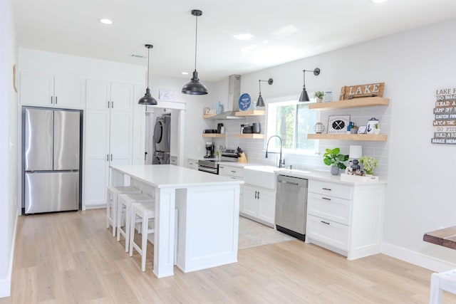 kitchen with stacked washer / drying machine, wall chimney range hood, stainless steel appliances, and open shelves