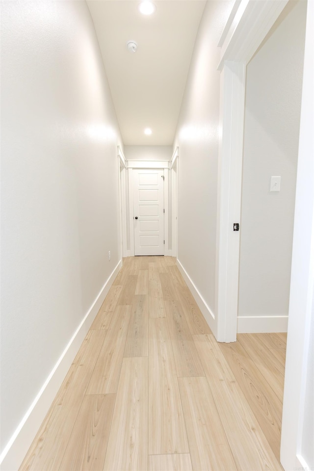hallway with baseboards, light wood-style floors, and recessed lighting