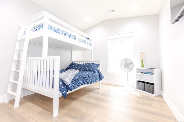 bedroom featuring baseboards, visible vents, vaulted ceiling, and wood finished floors
